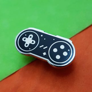 black video game controller shaped enamel pin adorned with silver startars